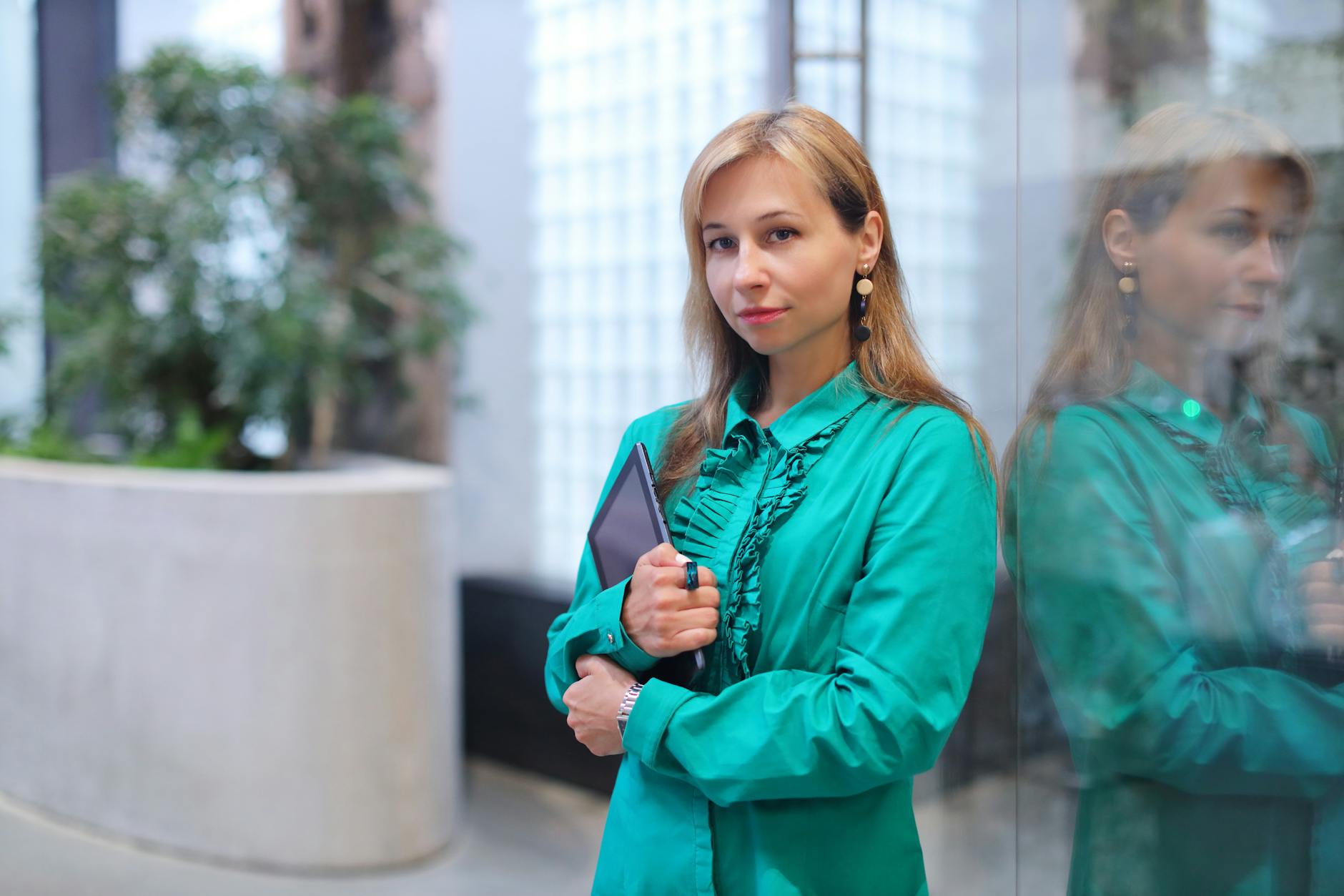 blonde woman in turquoise blouse with a tablet in her hands