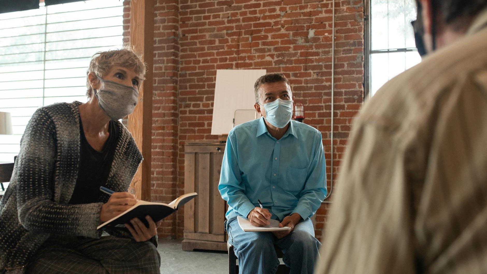man and woman listening at the person while writing on notebooks